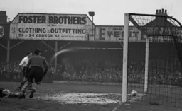 The outstretched leg of Leeds centre half Jim McCabe has just diverted the ball into his own net. Jesse Pye is on hand to make sure it is a goal.