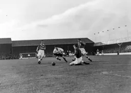Joe Scott chases the ball as Gil Merrick rushes out to smother it