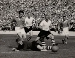 Ron Baynham dives bravely at feet of Stuart Leary