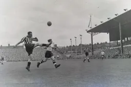Looks like Frank Brennan is about to kick Peter MacEwan`s head off but he is merely clearing the ball