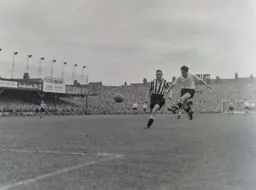 Gordon Turner leaves Frank Brennan in his wake to fire in a shot at goal