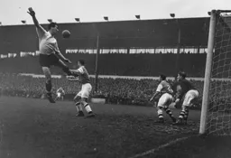 Jimmy Adam leaps for the ball but the Arsenal defence follow its progress