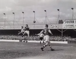 Roy Davies beats Bob Seith to the ball to send a header towards goal