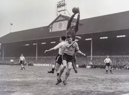 City keeper Sandy Kennon leaps high above Bob Morton to claim the ball