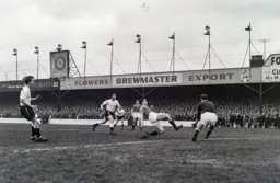 Billy Foulkes at full stretch clears the ball away from the on rushing Bob Morton