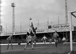 Terry Carling punches the ball away from the head of Keith Allen