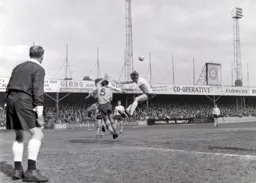 Alex Gibson heads the ball clear away from Keith Allen