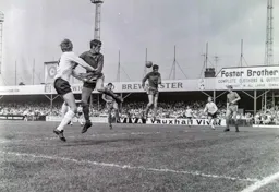 The ball is headed clear with Keith Allen and Laurie Sheffield close at hand