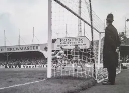 Malcolm Macdonald tries to get his boot to the ball watched by the long arm of the law