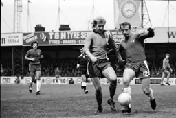 Ron Futcher challenges Peter Houseman for the ball