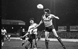 Mick Harford watches the defender clear