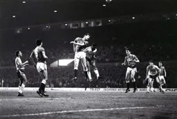 Ricky Hill and Norman Whiteside leap high but the ball has gone