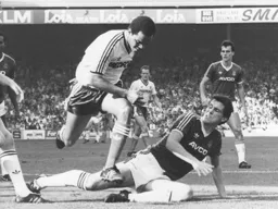 Brian Stein hurdles over the outstretched legs of Tony Gale