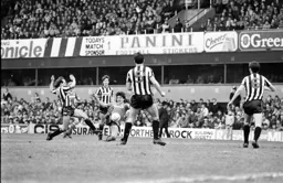 Mick Harford plays the ball as he goes to ground as David McCreery moves in