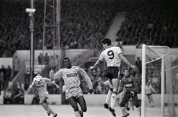 Mike Newell heads the ball down in front of Mitchell Thomas