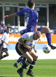 Lucas Neill rises and Matt Taylor ducks
