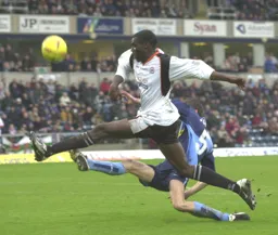 Enoch Showunmi and Roger Johnson are at full stretch to win the ball