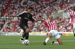 Carlos Edwards controls the ball as a Stoke defender slides in