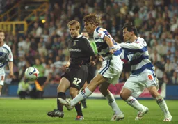 Peter Holmes passes under pressure from two QPR players