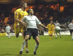 Warren Feeney challenged by a Preston player