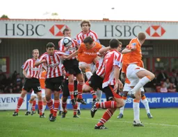 Tom Craddock wins a header in a crowded penalty area