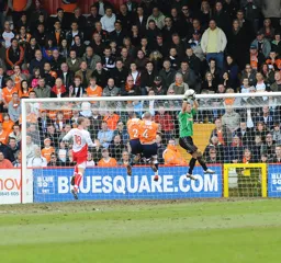 Everybody gets airbourne as Mark Tyler safely catches a cross into the box