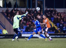 Rhys Taylor gathers the ball as Andre Gray closes in