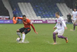 Andre Gray contends with the wet pitch