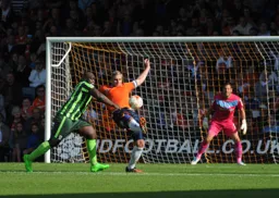 Steve McNulty clears the ball under pressure from Ade Akinfenwa