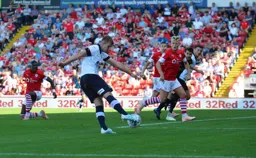 James Bree sends in a cross, former Hatter Cameron McGeehan looks on