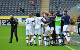 Everyone bundles in, players, substitutes and coaches to celebrate, but Nathan Jones is telling everyone to remain calm