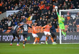 The Blackpool keeper forced into a tremendous save as Elijah Adebayo and Jordan Clark watch on