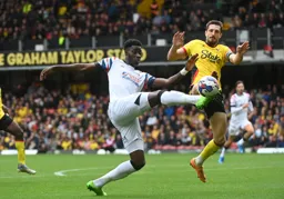 Elijah Adebayo goes for the ball under pressure from Craig Cathcart