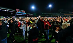 Fans celebrate on the pitch after the game