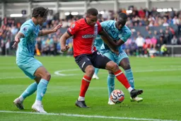 Carlton Morris holds off two Wanderers defenders